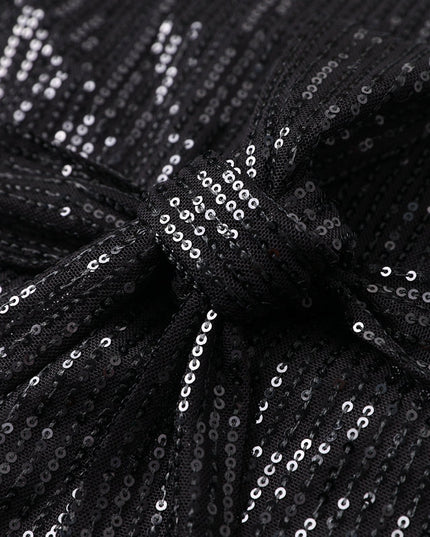 Woman wearing sparkling sequin mini dress with waist tie detail